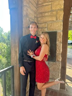 a man in a tuxedo and a woman in a red dress pose for a photo