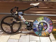 a bicycle parked on the side of a street next to a pole with an advertisement painted on it