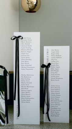 two white cards with black ribbons tied to them