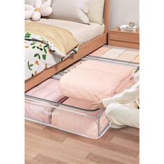 an open drawer on the floor in front of a bed with pink sheets and pillows