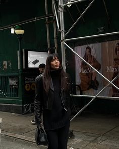 a woman is walking down the street in black