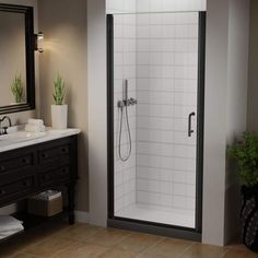 a bathroom with a walk in shower next to a white sink and black vanity mirror