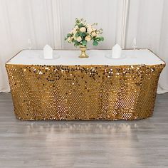 a gold sequin table cloth with candles on it and flowers in the centerpiece