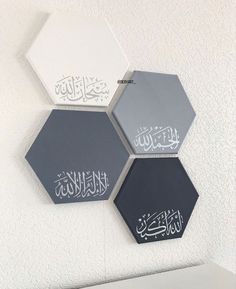 three hexagonals with arabic writing on them are hanging on the wall next to each other