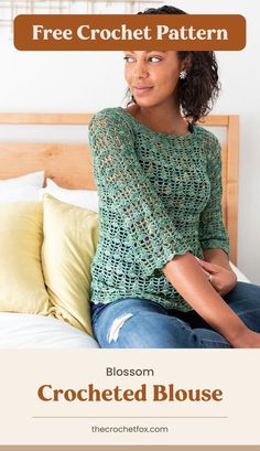 a woman sitting on top of a bed wearing a green crocheted sweater and jeans