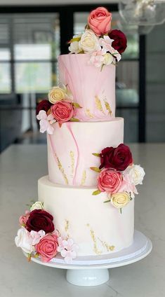 a three tiered cake with pink and red flowers