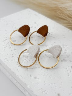 three pairs of gold and white earrings sitting on top of a table next to fur