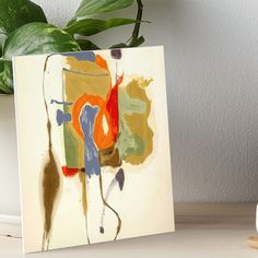 an abstract painting is displayed on a table next to a potted plant art board print