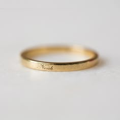 a gold wedding ring with the word noah engraved on it's side, sitting on a white surface