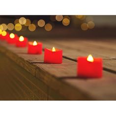 lit candles are lined up on a wooden table