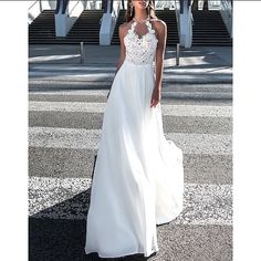 a woman in a white dress standing on the street