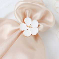 a white flower sitting on top of a pink satin bag