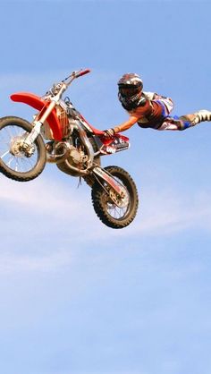 a man flying through the air on top of a dirt bike in front of a blue sky