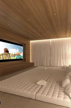 a large bed sitting in front of a flat screen tv on top of a wooden wall