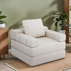 a white chair sitting on top of a rug next to a wooden dresser and potted plant