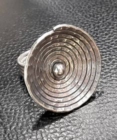 a metal object sitting on top of a black table with a silver ring in it's center