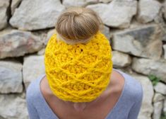 a woman wearing a yellow crocheted headband with her hair in a bun