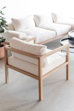 a white couch sitting next to a black table with a potted plant on it