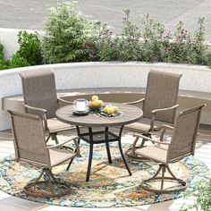 a round table with four chairs around it on top of a rug in the middle of a patio