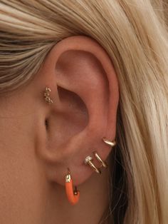 a close up of a woman's ear with three different piercings on it