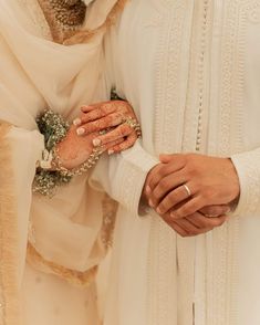 two brides holding hands in front of each other with their wedding rings on them