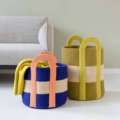 three colorful baskets sitting next to each other on the floor in front of a couch