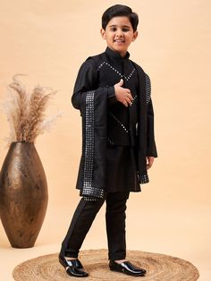 Vastramay Boy's Black Mirror Work Jacket And Solid Kurta Pyjama Set With Black Ethnic Dupatta A stylish and traditional ensemble for boys, this set features a black mirror work jacket paired with a solid kurta pyjama set and a black ethnic dupatta. The jacket is intricately designed with mirror work, adding a touch of elegance. The kurta and pyjama are solid black, complementing the jacket perfectly. The set is perfect for festive occasions and celebrations. Features: Includes jacket, kurta, pyj Bollywood Style Festive Winter Sets, Black Embroidered Nehru Jacket For Diwali, Embroidered Black Nehru Jacket For Diwali, Fitted Churidar With Traditional Patterns For Diwali, Diwali Fitted Churidar With Traditional Patterns, Traditional Patterned Long Sleeve Churidar For Festivals, Long Sleeve Churidar With Traditional Patterns For Festivals, Long Sleeve Choli With Dabka For Diwali, Designer Dabka Choli With Long Sleeves