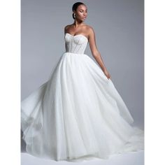 a woman in a white wedding dress posing for the camera with her hand on her hip