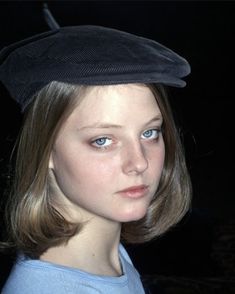 a young woman wearing a black hat and blue shirt is looking at the camera with an intense look on her face