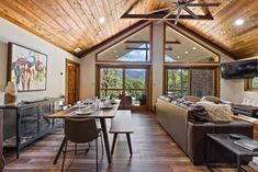 a living room filled with furniture and a flat screen tv mounted on the wall next to a wooden ceiling