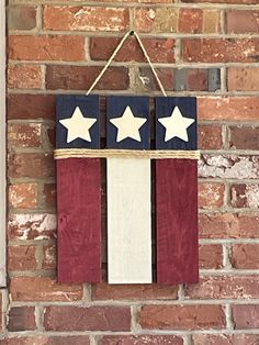 an american flag made out of wood hanging on a brick wall with three white stars