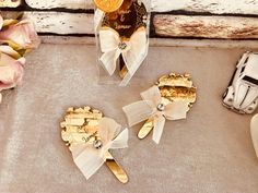 three pieces of gold and white hair clips sitting on top of a table next to flowers