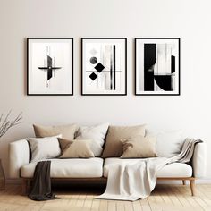 three black and white paintings hang on the wall above a couch in a living room