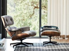 an eames chair and ottoman in front of a window