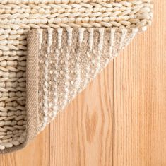 an area rug on the floor with wood in the background and light colored carpeting