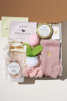 an open box containing pink items and a potted plant in the middle with gold foil around it