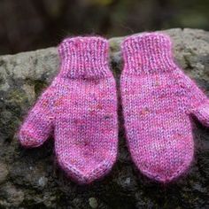 two pink mittens sitting on top of a rock