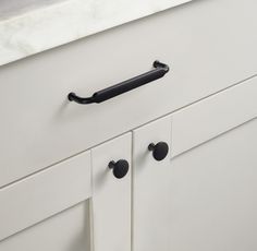 an image of a kitchen cabinet door handle on the front of a white cupboard with black handles