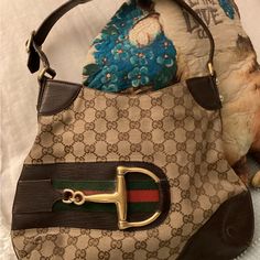 Signature Brown Canvas, Snap Top, Inside Zip Pocket, Adjustable Strap, Used, Shows Signs Of Usage, Canvas Is Worn On Back, White Stain On Back And On Lining, Might Could Be Cleaned, Otherwise Good Clean Used Condition, 13” Long, 10” Tall. Still A Very Attractive Bag, Sure To Get Many Compliments! Gucci Horsebit Bag, Bags Gucci, Gucci Horsebit, White Stain, Brown Canvas, Gucci Bag, Zip Pockets, Adjustable Straps, Stain