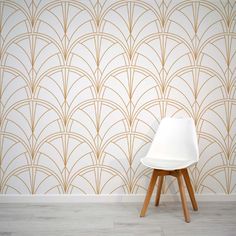 a white chair sitting in front of a wall with gold art deco designs on it