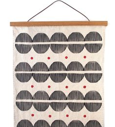 a black and white wall hanging on a wooden frame with red dots in the middle