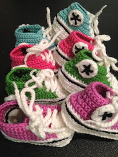 several crocheted baby shoes are stacked on top of each other, one is pink and the other is green