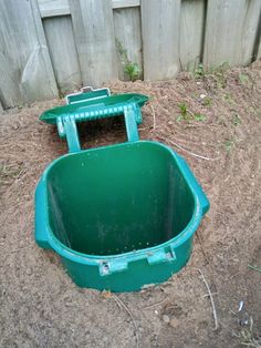 an empty green container sitting in the dirt