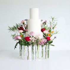 a white wedding cake with flowers in vases