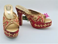 Our new collection of wedding shoes which we offer for you. These feature zardozi hand embroidered design on raw silk fabric. They are a red with beautiful design imbedded with gold rhinestones and gold zari work in the shape of leaves along with zari and gold rhinestones border on platform base. They feature a round toe chunky heel design. They have a heel design measuring 5 inches from bottom of heel to top of heel and platform base in front of 1 inch. They are comfortable to wear all day. The Gold Open Toe Block Heels For Wedding, Designer Red Heels For Wedding, Festive Wedding Shoes With Dori Work For Party, Festive Party Wedding Shoes With Dori Work, Festive Open Toe Wedding Shoes With Gota Work, Gold Embroidered Open Toe Heels, Traditional Open Toe Heels For Festive Occasions, Traditional Open Toe Heels For Party, Traditional Open Toe Wedding Heels