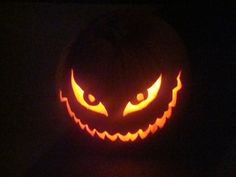 a carved pumpkin with an evil face on it's side, lit up in the dark