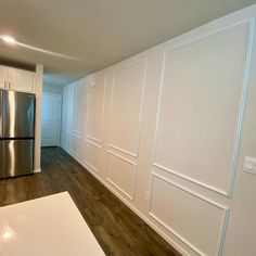 an empty kitchen with white walls and wood floors