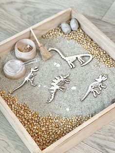 a wooden box filled with different types of dinosaurs and other things to make it look like they are making something out of sand