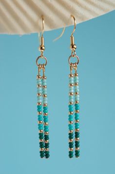 two blue beads hanging from gold plated earrings