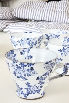 six blue and white cups sitting on top of each other next to a striped pillow